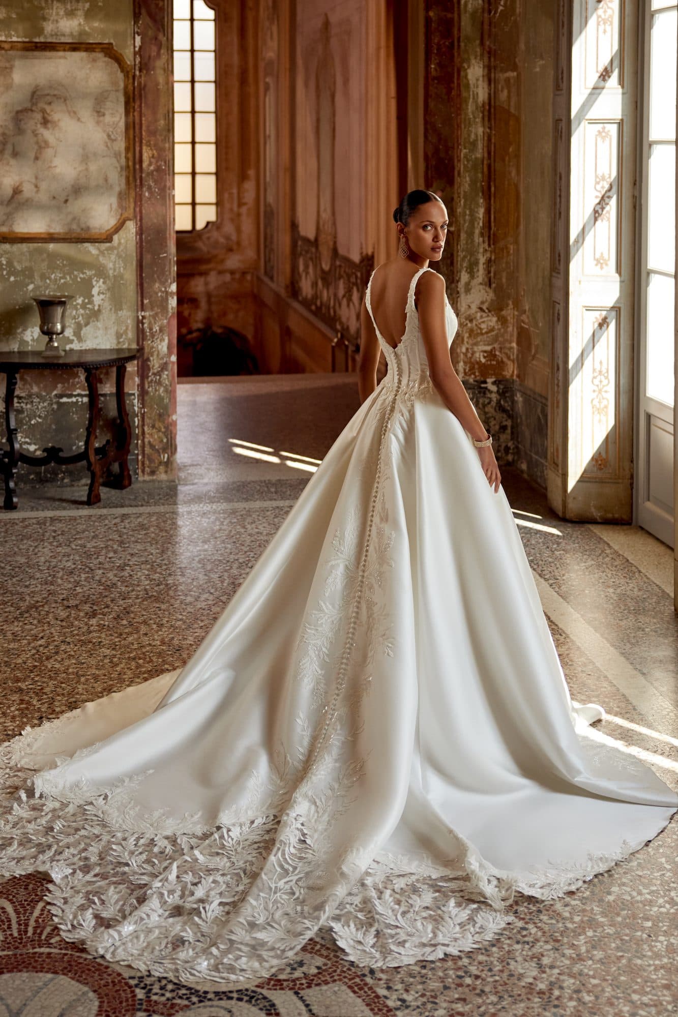 Back of the Justin Alexander Keegan gown showing its buttoned V-back and lace-edged train.