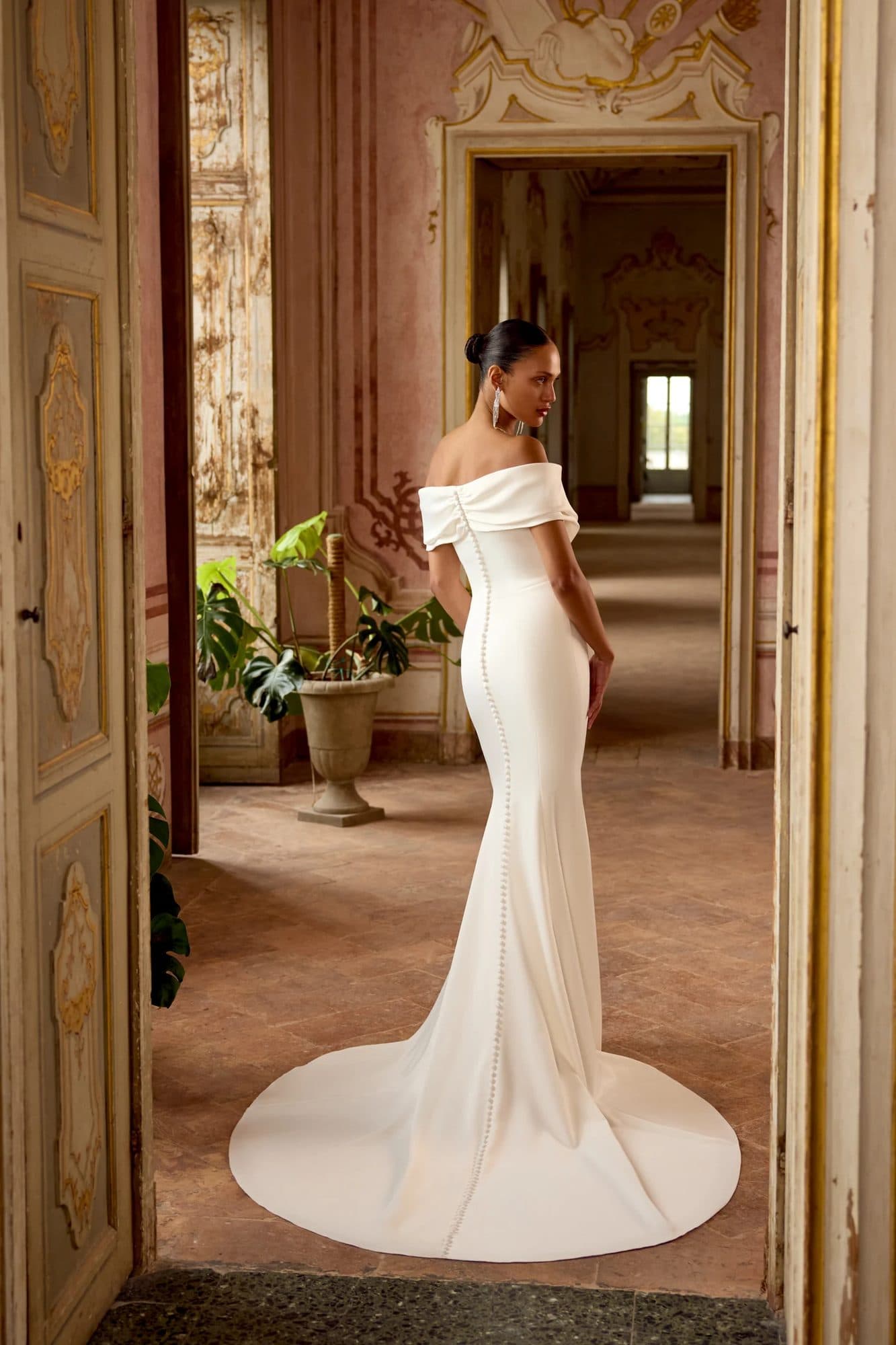 Back of the Justin Alexander Kori gown showing its folded off-the-shoulder band and buttoned seam down the train.