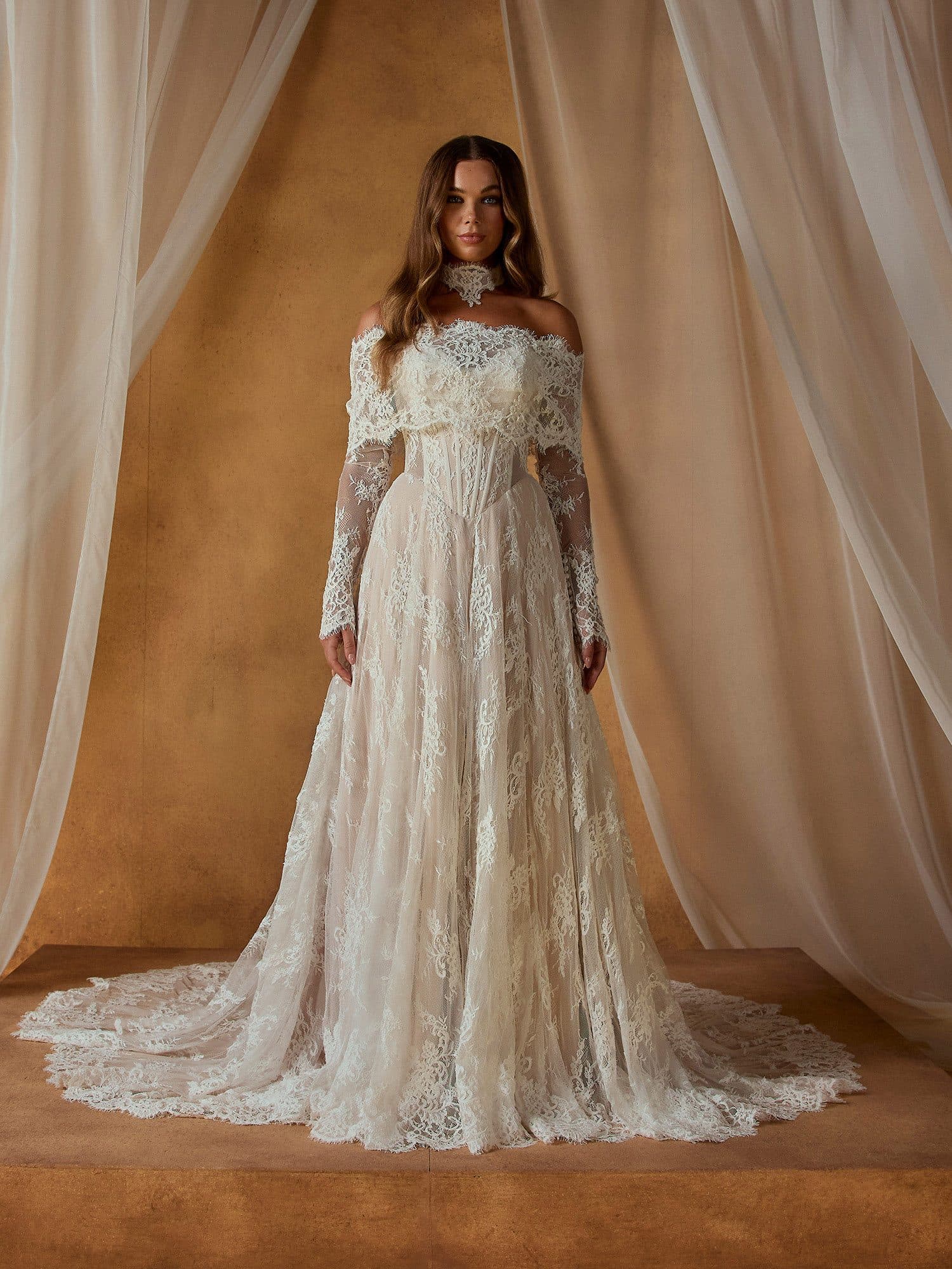 Front of the Madi Lane Nivaya gown, an antique-toned lace A-line with long off-the-shoulder sleeves.