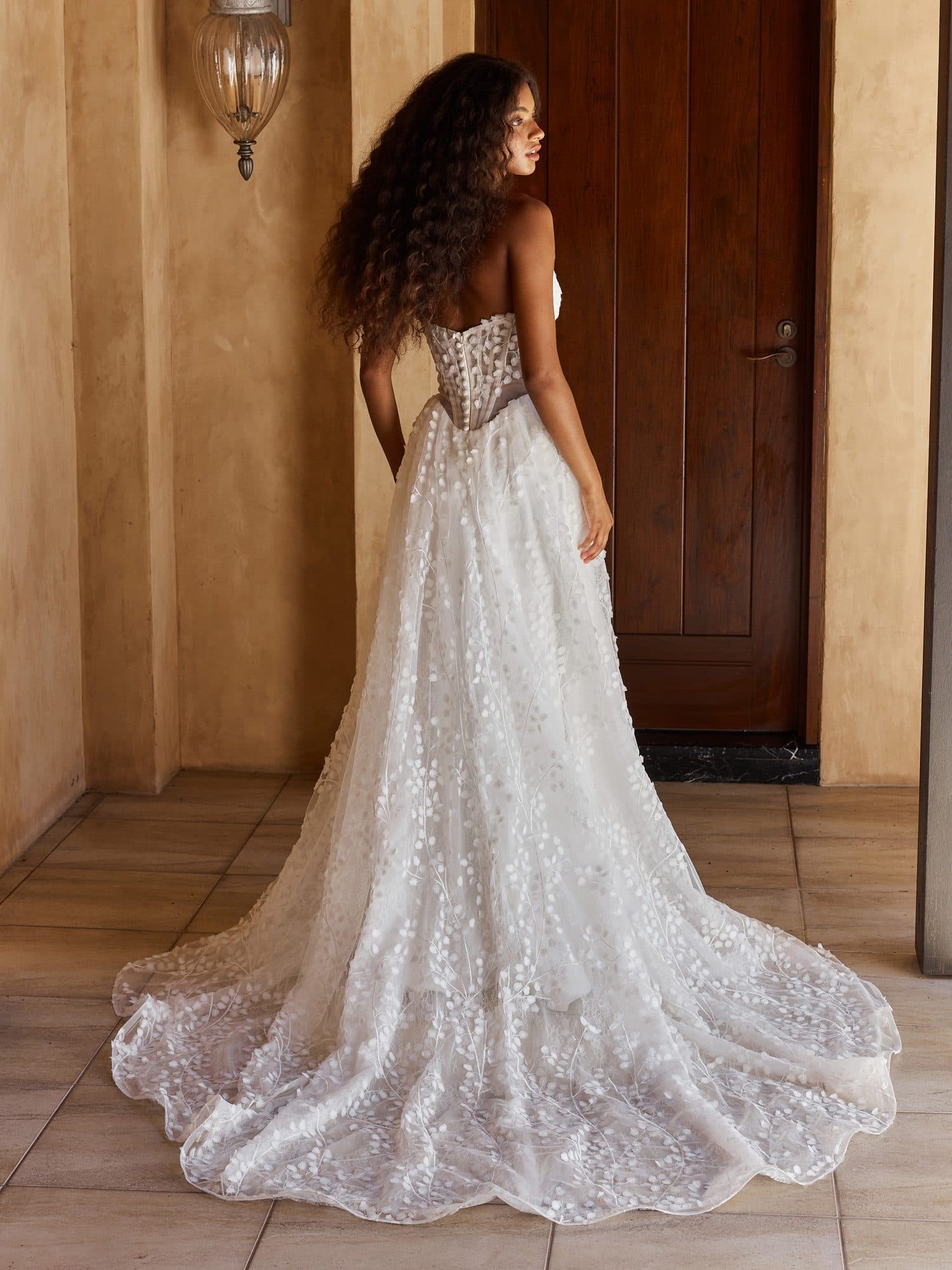 Back of the Madi Lane Oriel gown showing its sheer corseted back and floral train.