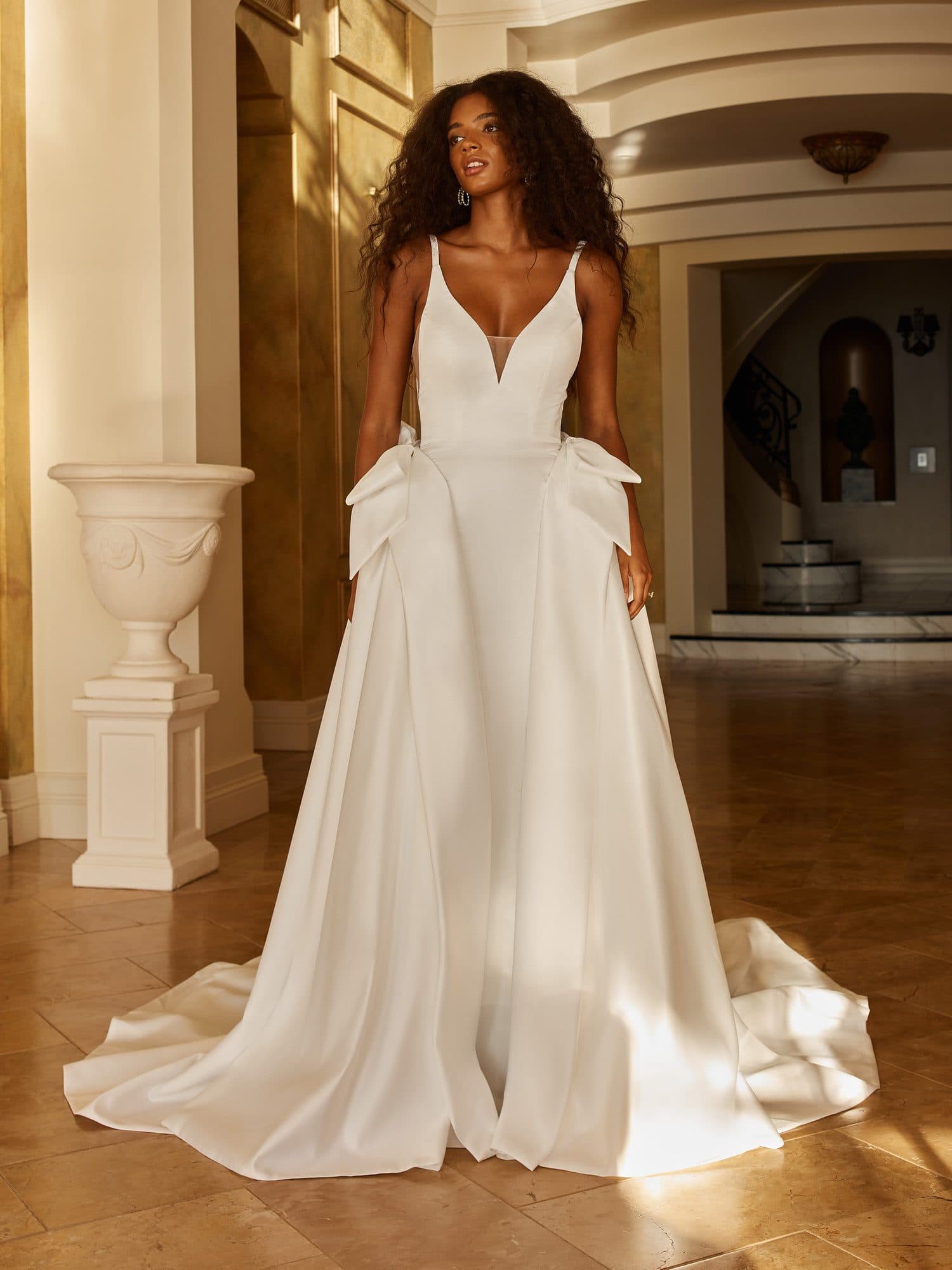 Front of the Madi Lane Osborne gown, a V-neck crepe silhouette with sculpted bows at the hips.