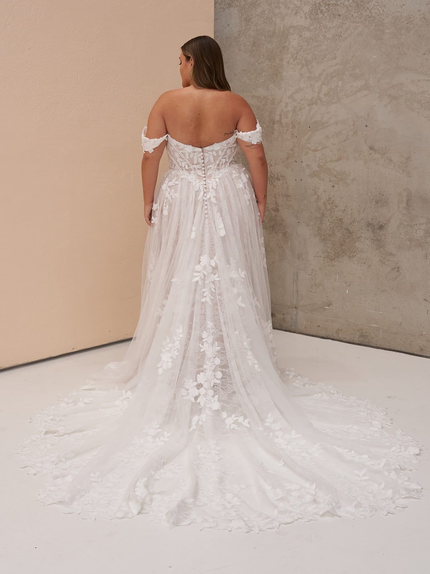 Back of the Madi Lane Osha gown showing its low back and long floral lace train.