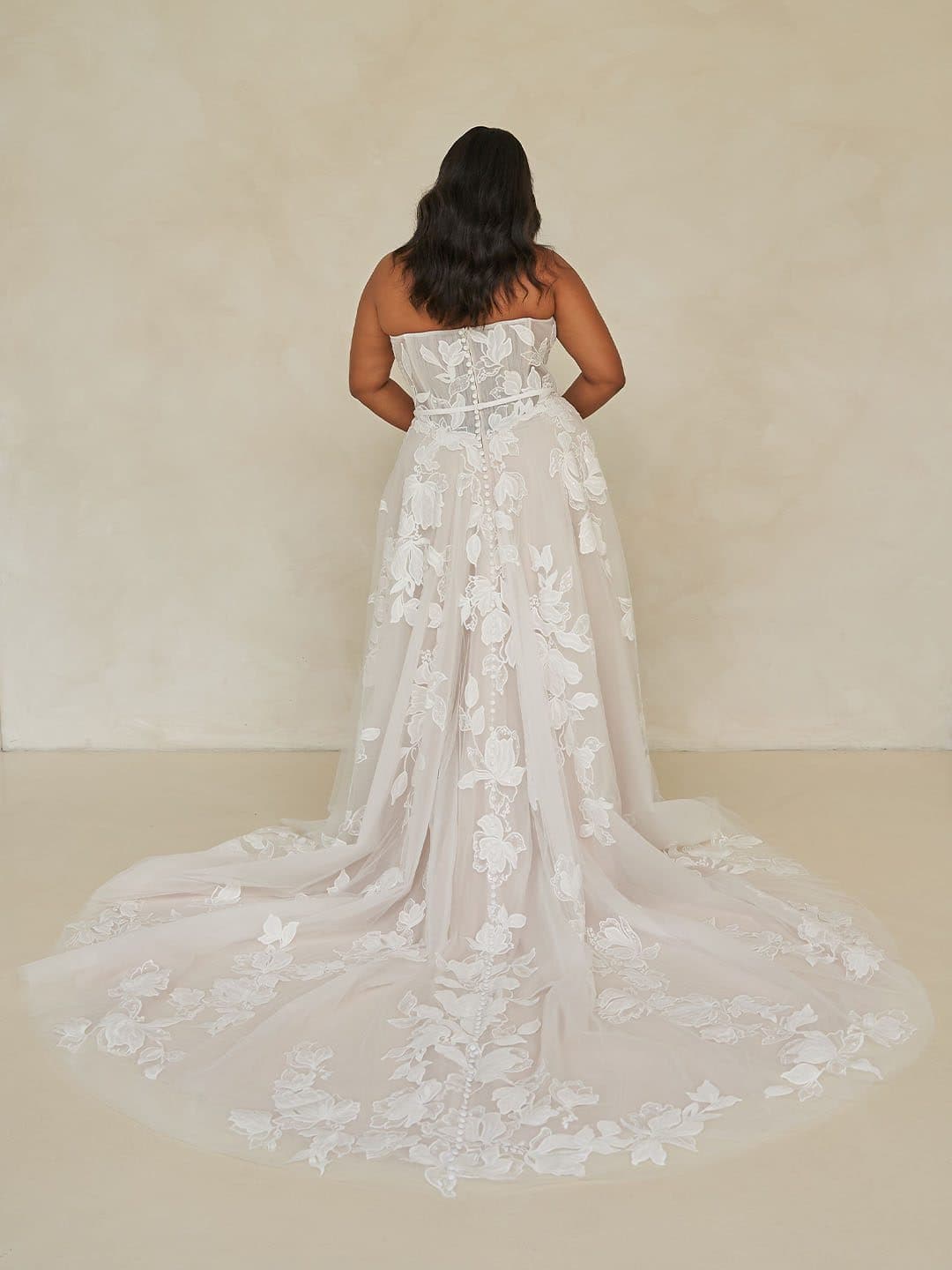 Back of the Madi Lane Walker gown showing its buttoned back and full floral lace train.