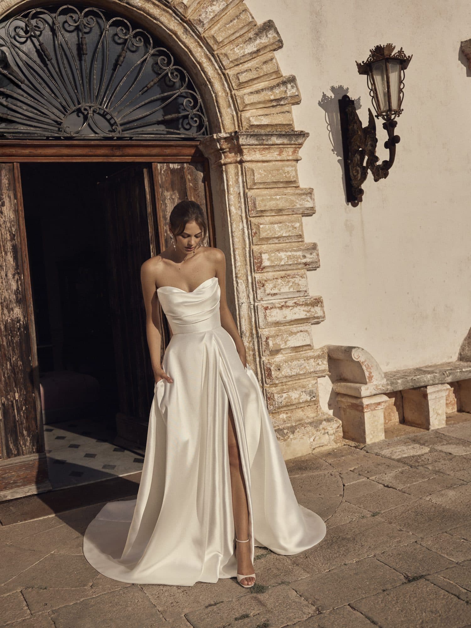 Front of the Modeca Marcella gown, a draped satin sweetheart silhouette with a high slit and pockets.